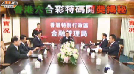 六名冒牌「金管局董事」在會議室開會，背後為寫有「香港特別行政區金融管理局」的布景板，以增加短片的可信程度。