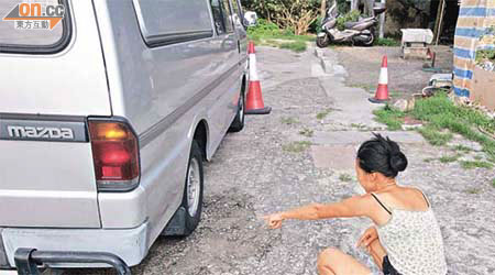 女戶主指示被熏黑的客貨車。	（張曉楠攝）