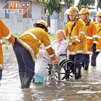 消防員協助坪輋坐輪椅老翁逃離遭淹浸的住所。（鄭家如攝）