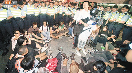 坐在馬路上的遊行人士被警員團團包圍。	（陸智豪攝）