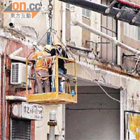 工人登上用吊臂吊住的工作台，用切割器清理外牆搖搖欲墜物件。（林明強攝）
