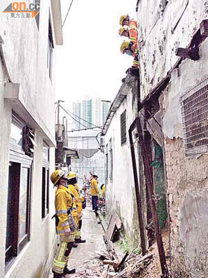 消防員在村屋塌牆現場調查。	（左錦鴻攝）