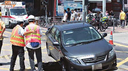 私家車右前轆陷入地洞，車身傾側。（林少兒攝）