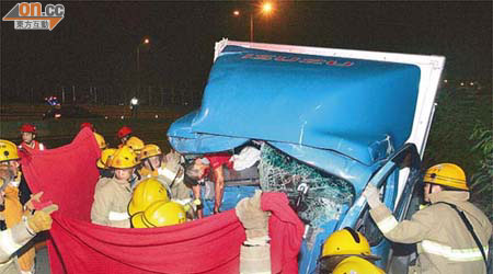 運報紙貨車司機被夾於嚴重損毀駕駛室，消防員設法將他救出。	（邱國賢攝）