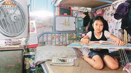 玥珊與父母（下圖）同住一個百多呎單位，她在睡床的桌子上做功課和看書。	（翁志偉攝）