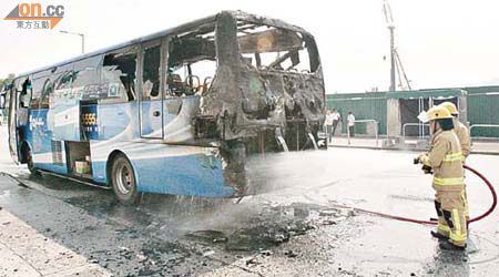 消防員向旅遊巴士的車尾着火位置射水。	（左錦鴻攝）