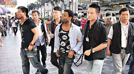 其中一名騙徒被警員用繩綁腰押返重慶大廈搜查。	（郭垂垂攝）