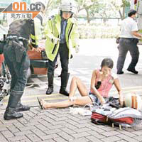 跑馬地電單車交通意外，女乘客坐在路邊接受包紮。	（馬竟峯攝）