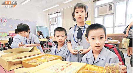覃浩龍（右三）、覃浩瑩（右二）、覃浩進（右一）三姊弟新學期開始每人獲送贈一盒月餅。	（陳德賢攝）