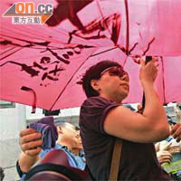 一名女子用寫有「支持曾偉雄」大字的紅雨傘，襲擊遊行人士和記者。