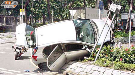 私家車剷上花槽再撞毀路牌，幸未有衝入行人路。	（許錦雄攝）