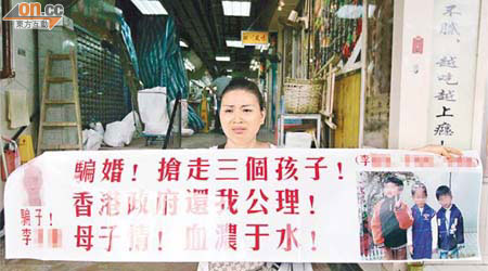 內地婦人手持橫額於港漢住所樓下抗議。	（李豪杰攝）