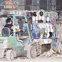 工人用鏟車將一捆捆洋垃圾剷起，方便探員搜尋垃圾內的毒品。（林明強攝）