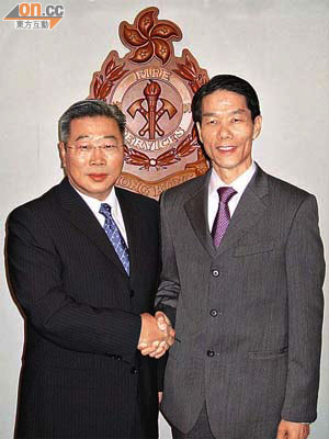 即將退休嘅盧振雄（右）與候任處長陳楚鑫握手以示順利交接。	（盧怡安攝）