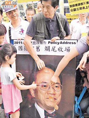 示威者在曾蔭權肖像貼紙雞蛋，象徵施政報告得分「零蛋」及想向曾蔭權掟雞蛋。	（許紹基攝）