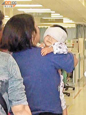 被唐狗咬傷頭的男嬰由母親抱着送院。	（黃君堡攝）
