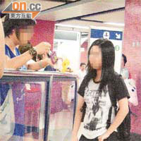 一名年輕女賣家（右），在港鐵旺角站閘內將煙花取給買家檢查。