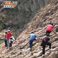 遊客徒手攀爬岩石進入海蝕洞參觀，險象環生。