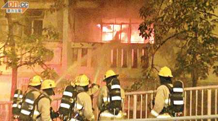 消防員在華富邨向起火的「垃圾屋」射水撲救。（張曉楠攝）