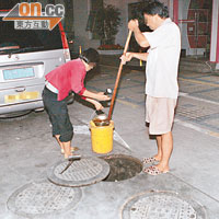 福田直擊．21:00<br>另一對男女打開污水渠蓋，用長柄杓子將地溝油撈進膠桶。