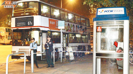 裝有子彈等武器的斜揹袋被人棄置在巴士總站的公共電話亭內（箭嘴示），警員封鎖現場。（高偉明攝）