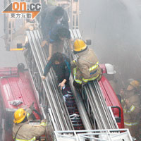消防員冒濃煙升起雲梯，營救被困的居民。