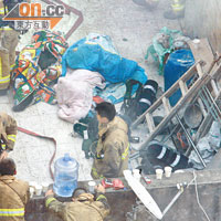 火場天台變臨時停屍間，疲於奔命的消防員在遇難者遺體旁小休。（許錦雄攝）