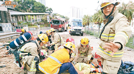 其中兩名工人被炸至飛彈出馬路浴血，由消防及救護員急救。（梁少恒攝）