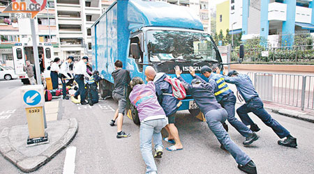 六名大漢合力將貨車推後，救出被車輪壓着的老翁。（左錦鴻攝）