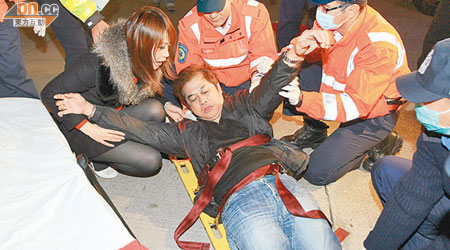 被九巴撞傷的休班車長拒絕救護員包紮，女兒在旁安慰。（馮戈攝）
