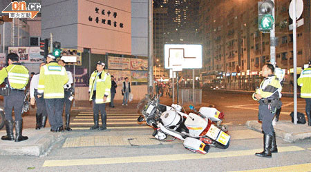 肇事交通警員電單車翻側路中。（馮戈攝）