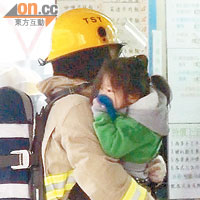 一名女童由消防員抱離險境。 