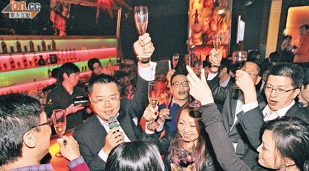 逾百賓客喺洪為民（持咪者）帶領下，高舉酒杯迎2012年，不醉無歸。（林少權攝）