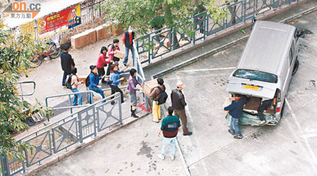 多名水貨客於富泰邨停車場旁空地，組成人肉運輸帶，合力卸貨。