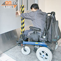 坐電動輪椅的曾先生需費力才能推開防火門，手推輪椅者更為吃力。