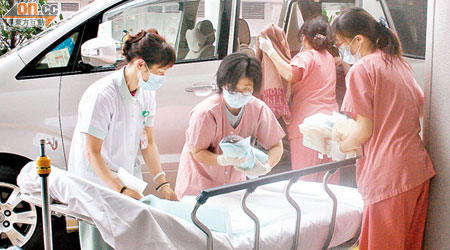 在車上出生的女嬰由醫護人員抱出，送入院作進一步檢驗。（張嘉怡攝）