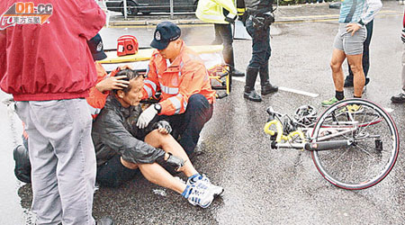 備戰鐵人賽炒單車受傷的六旬車手，由救護員急救。「戰車」翻側路上。（陳振傑攝）