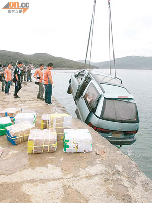 警方將墮海的七人車吊起，岸邊遺下多箱走私貨品。（吳華盛攝）