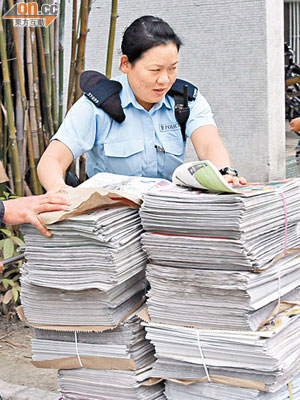 警員用手推車將被人變賣的免費報章運走。（麥少峰攝）