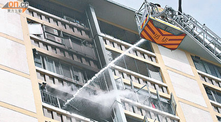 消防員升起雲梯向火場射水灌救。