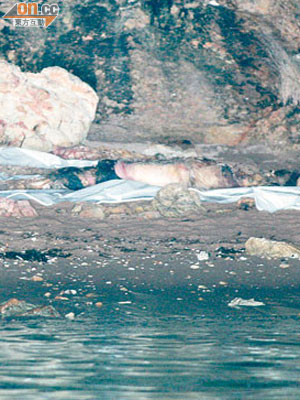 在娥眉洲發現的女屍由警員移至岸上石灘，身上部分衣服被脫下。（李健瑜攝）