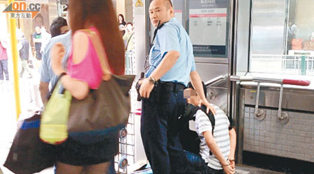 警員將被捕扒手按坐在港鐵站出口梯級。