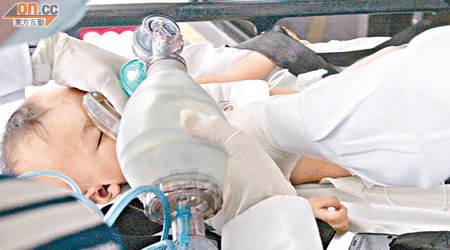 救護員用氧氣罩協助昏迷男嬰呼吸。