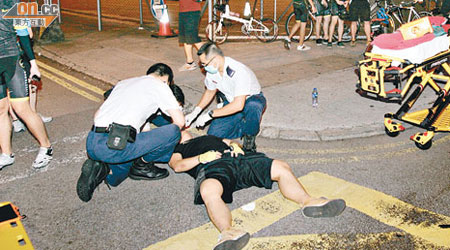 受傷男子倒臥地上，救護員為他檢查及包紮。（梁國雄攝）