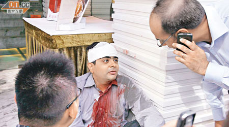 遇劫印度男子頭破血流，衣衫染血，同事趕至協助。（周景文攝）