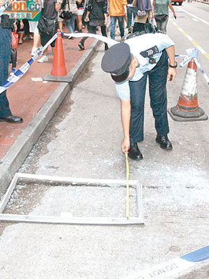 警員檢查墮街的鋁窗。（吳遠輝攝）