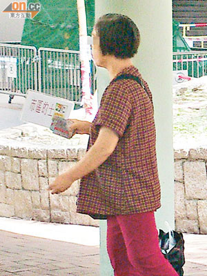 大埔墟港鐵站對開，有女子一邊手持七折的士宣傳牌，一邊向途人派發卡片。
