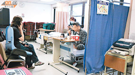 病房活動區也設有臨時病床，訪客要在堆高的膠椅上坐。（朱先儒攝）