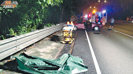 當場死亡的司機屍體以膠布遮蓋，涉意外的私家車橫亘路上。（左蘭慶攝）