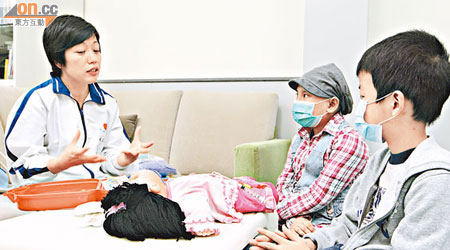 呂思華（左）運用布偶向兩位病童講述治療程序。（陳錦輝攝）